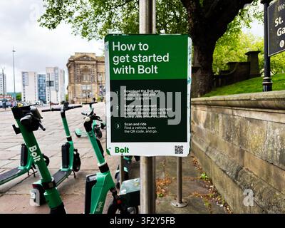 Liverpool, UK - 16 maggio 2026: Scooter elettrici Green Bolt parcheggiati vicino a un cartello con istruzioni di noleggio vicino a edifici storici a Liverpool, UK. Foto Stock
