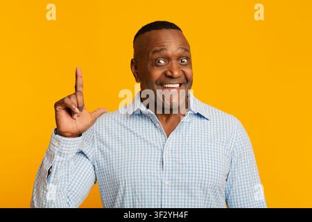 Allegro africano di mezza età che punta il dito verso l'alto Foto Stock