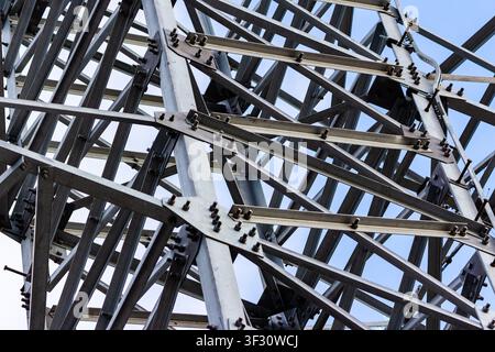 Vista ravvicinata di una torre di trasmissione elettrica ad alta tensione con una complessa struttura a griglia in acciaio zincato e connessioni bullonate resistenti a Foto Stock