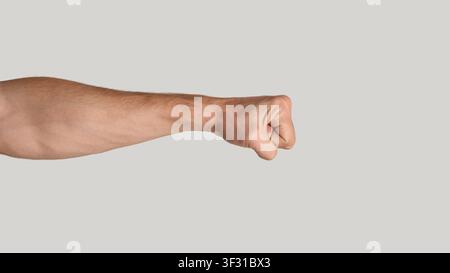 Uomo millenario pugno clenching su sfondo grigio chiaro, primo piano. Spazio di copia. Panorama Foto Stock