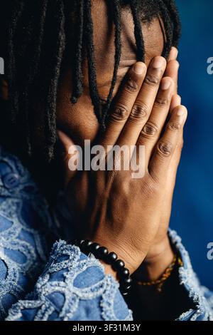 Uomo nero che copre il viso mentre esprime stress e ansia Foto Stock