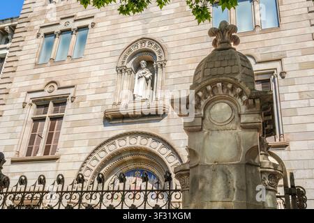 Barcellona - Spagna - 23 maggio 2026: Facciata neogotica ornata del Palazzo Vescovile, statua in pietra in una nicchia, arco scolpito e recinto in ferro battuto Foto Stock