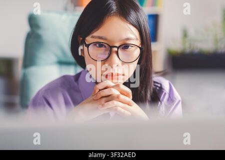 Donna asiatica concentrata che lavora su un laptop in un ufficio moderno, concetto aziendale Foto Stock