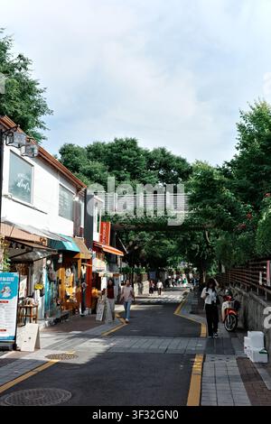 Pedoni su una strada commerciale fiancheggiata da caffè con insegne di negozi, Seoul, Corea del Sud Foto Stock