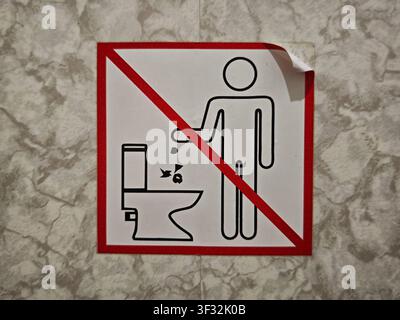 Un cartello ricorda alle persone di non gettare spazzatura nel water in un bagno pubblico. L'immagine mostra una semplice grafica di una persona e di un gabinetto. Foto Stock