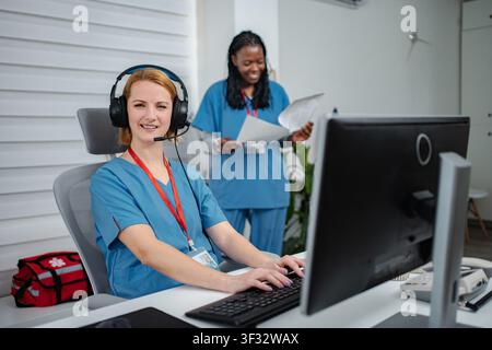 Dispatcher medico donna che indossa la cuffia che lavora al computer Foto Stock