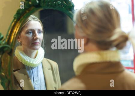 Donna davanti a uno specchio ornato Foto Stock