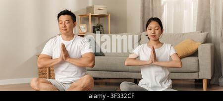 Donna e uomo asiatici che praticano yoga insieme a casa, concetto di consapevolezza positiva Foto Stock