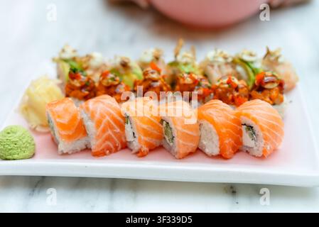 Rollini di sushi al salmone fresco su un piatto bianco con cucina giapponese a base di frutti di mare di qualità. Otto pezzi di nigiri premium in una presentazione appetitosa. Ingredienti crudi di alta qualità con maestria culinaria Foto Stock