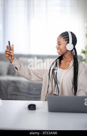 Giovane donna adulta che scatta selfie con cuffie e telefono Foto Stock