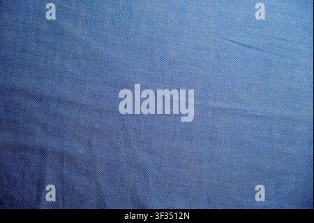Sfondo in tessuto di cotone blu con pieghe morbide increspate. Foto di alta qualitàPrimo piano a campo completo di una texture di tessuto a maglia o tessuta blu chiaro con pieghe morbide naturali e ombre. Sfondo astratto moderno adatto per moda, concetti tessili, abbigliamento sportivo, design di banner o modello di abbigliamento. Foto Stock
