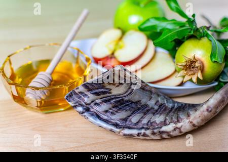 Simboli di Rosh Hashanah tra cui shofar, miele, mela e melograno su una superficie di legno Foto Stock