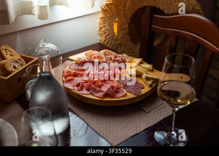 Tavola di salumi abbondante con misti di salumi — prosciutto crudo, salame, speck o coppa — e formaggi (grana, semi stagionati) nelle trattorie rustiche italiane Foto Stock