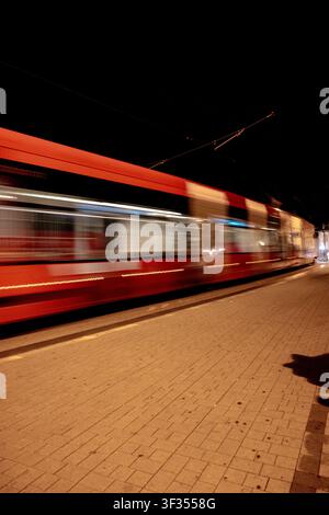 Tram rosso sfocato dal movimento durante un'esposizione lunga su una strada di Bratislava di notte, Slovacchia. Foto Stock