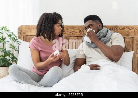 Malato afroamericano avvolto in sciarpa seduto a letto Foto Stock