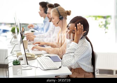 Afro americano operatore di helpline si sente sfinito dopo aver parlato con i clienti al call center, copia spazio Foto Stock