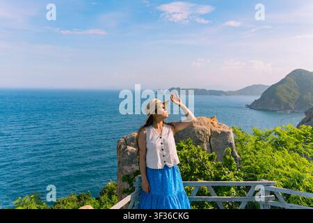 Donna che osserva drammatici isolotti rocciosi da un punto di vista costiero, isola Bich Dam, Nha Trang Foto Stock