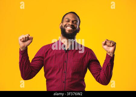 Felice uomo nero trionfante con mani sollevate Foto Stock