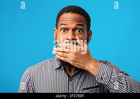 Divertente uomo nero che ricopre la bocca con la mano Foto Stock