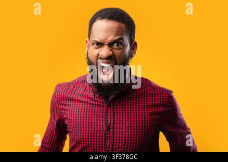 Arrabbiato afro uomo urlando allo studio giallo Foto Stock