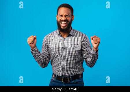 Felice uomo afro trionfante con mani alzate Foto Stock