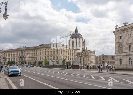 Berlino, Germania, 18 luglio 2026. Il palazzo di Berlino ricostruito e la sua cupola si ergono dietro il ponte del castello sotto nuvole drammatiche e una gru per costruzioni Foto Stock