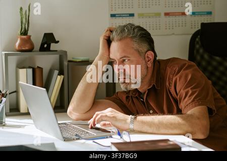 Insegnante di mezza età che lavora su un laptop in classe Foto Stock