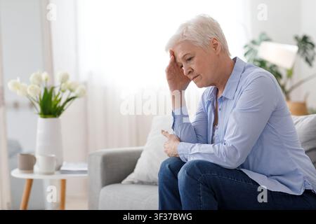 Donna Climax. Ritratto di depressa donna anziana seduta sul lettino a casa Foto Stock