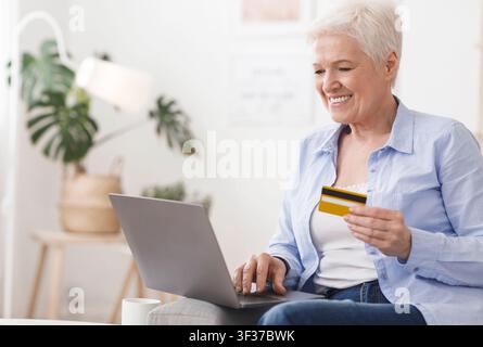 Acquista online. Donna anziana Shopping in Internet con laptop e carta di credito Foto Stock