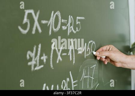 Insegnante che scrive equazioni matematiche alla lavagna per l'educazione Foto Stock