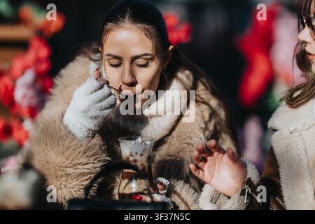 Donna che mangia un dessert con gli amici in un caffè all'aperto invernale, cappotti di pelliccia accoglienti e divertimento Foto Stock