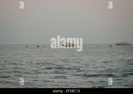 Naufragio di una barca parzialmente sommerso che mostra abbandono e decadimento in mare aperto Foto Stock