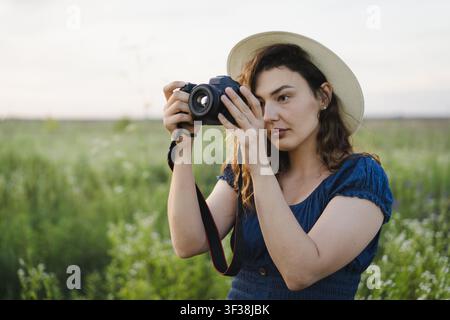 Fotografa sorridente che rivede le foto sulla fotocamera in un prato estivo Foto Stock
