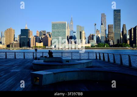 Queens, New York, USA - 21 luglio 2025: Persona solitaria che ammira lo skyline di Manhattan all'alba (New York, New York, USA) Foto Stock