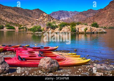 Kayak sulla riva rocciosa accanto al fiume Colorado con montagne del deserto e cielo blu limpido Foto Stock