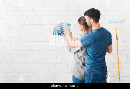 Coppia che sceglie il colore blu sulla tavolozza per dipingere le pareti Foto Stock