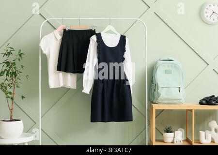 Uniforme scolastica per bambini appesa su una rastrelliera con zaino e scarpe Foto Stock