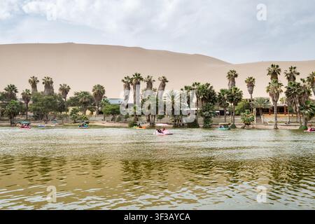 Huacachina, Ica, Perù - 14 ottobre 2018: Vista dell'oasi di Huacachina con laguna, palme, dune di sabbia e pedalò Foto Stock