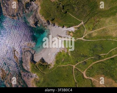 Vista aerea dall'alto della spiaggia di Lansallos che mostra la sua baia isolata con acqua turchese chiara, sabbia dorata, scogliere rocciose e sentieri costieri verdi. Foto Stock