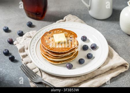 Dolce impilata di pancake fatti in casa con mirtilli, burro e sciroppo d'acero Foto Stock