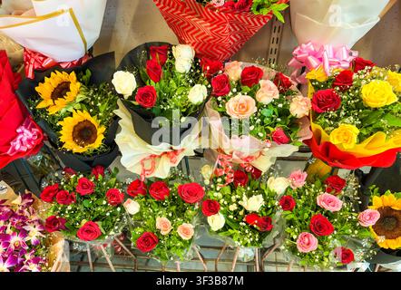 Composizioni floreali fresche con rose rosse, rose gialle e girasoli luminosi nel negozio al dettaglio Foto Stock