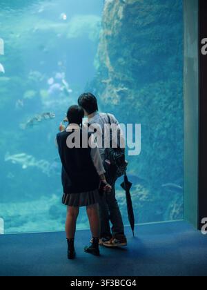 Due studenti delle superiori in uniforme che indicano pesci durante una visita al grande acquario oceanico di Fujisawa Foto Stock
