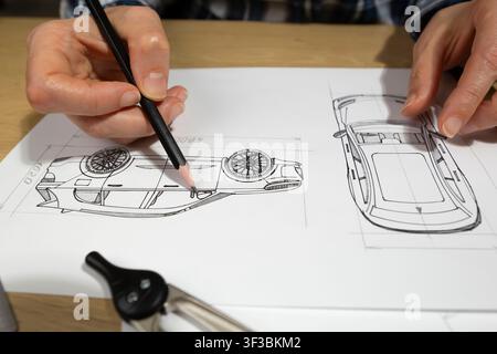 Mani di un ingegnere che disegna un prototipo di veicolo automobilistico con la matita su carta alla scrivania. Progettista industriale che sviluppa nuove bozze di progetti di auto vicino a me Foto Stock