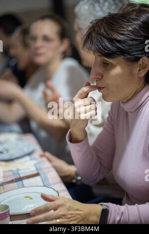 Anziana che gusta un pezzo di torta di compleanno durante una festa di famiglia per il compleanno Foto Stock
