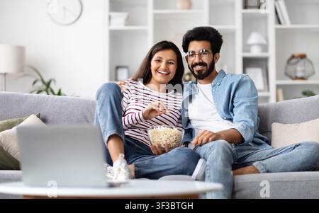 Felice coppia internazionale che guarda film sul computer portatile a casa Foto Stock