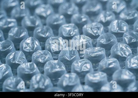 Immagine macro dettagliata di pluriball che mostra file di bolle di plastica gonfiate con poca profondità di campo e toni blu morbidi. Ideale per concetti di protezione delle confezioni, materiali di spedizione, logistica e sfondi industriali astratti. Foto Stock