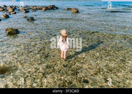 Donna che guadagna acqua chiara e bassa tra le rocce Foto Stock