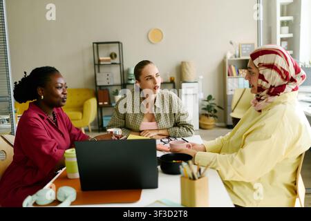 Donne d'affari diverse che collaborano in una riunione inclusiva in ufficio Foto Stock