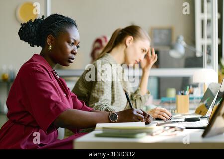 Donna nera che lavora con un collega stressato in una riunione d'ufficio Foto Stock