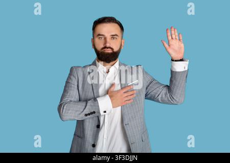 Ritratto di un giovane e serio congressista che giurava sullo studio blu sfondo Foto Stock